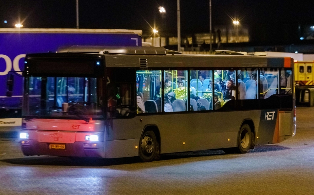 A bus with refugees drives away from the DFDS ferry, in the harbor of Vlaardingen, The Netherlands on Tuesday, after 25 stowaways were found onboard. -AFP