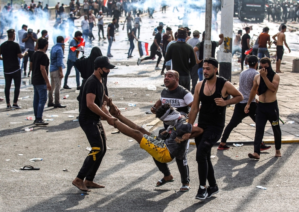 Iraqi protesters carry away an injured comrade amid clashes with riot police during a demonstration against state corruption and poor services, at Baghdad's Tahrir Square in this Oct. 1, 2019 file photo. — AFP