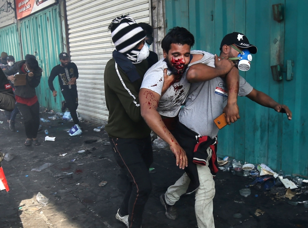 Iraqi protesters carry away an injured comrade amid clashes with riot police during a demonstration against state corruption and poor services, at Baghdad's Tahrir Square in this Oct. 1, 2019 file photo. — AFP