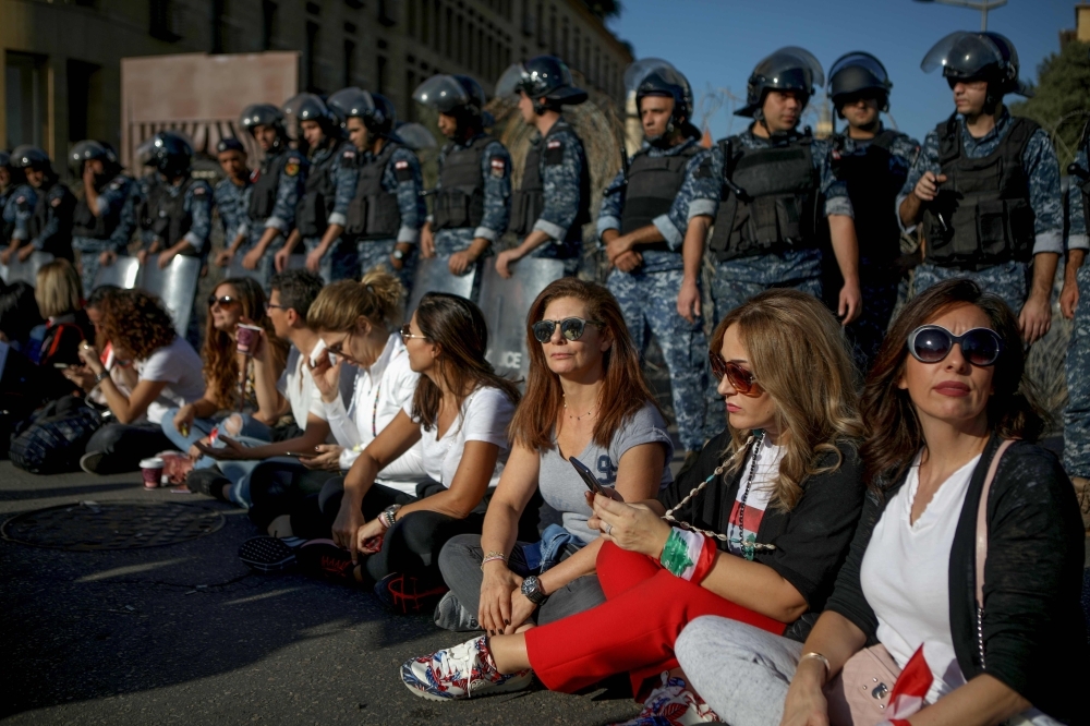 Lebanese anti-government protesters sit on the ground as they take part in a demonstration near the parliament headquarters in the capital Beirut's downtown district on Tuesday. — AFP