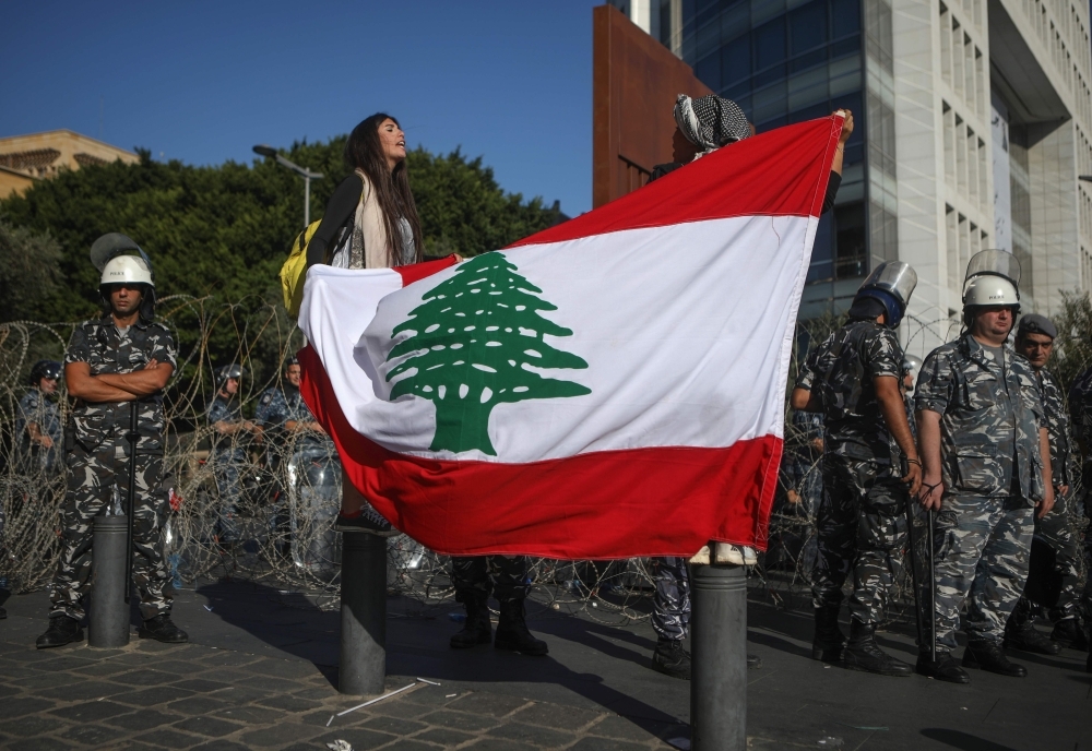 Lebanese anti-government protesters sit on the ground as they take part in a demonstration near the parliament headquarters in the capital Beirut's downtown district on Tuesday. — AFP