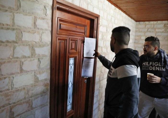 Palestinian employees of Palestine TV channel inspect a notice of closure at the door of the station's office after it has been raided by Israeli forces in East Jerusalem on Wednesday. — AFP