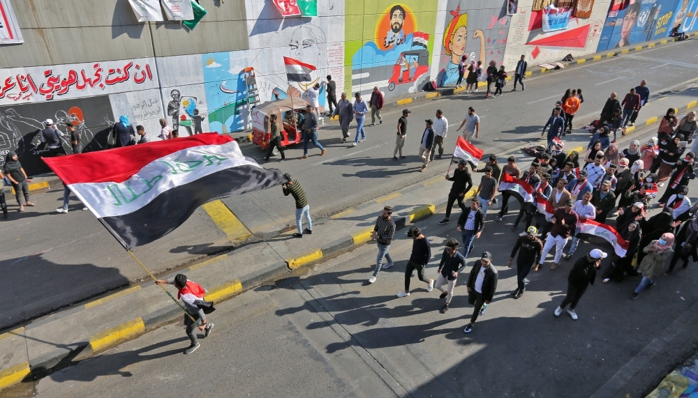 Iraqi youths waving national flags march through Tahrir Square in the Iraqi capital Baghdad as anti-government protests continued across the country on Wednesday. — AFP