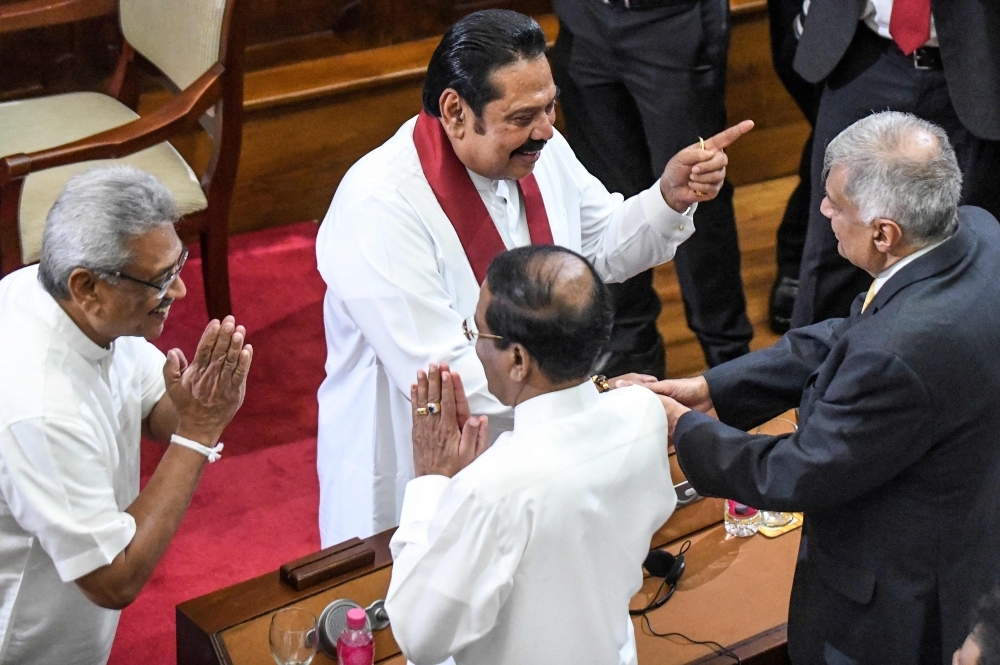 Sri Lanka's former President Mahinda Rajapaksa, second left, who was appointed new country's Prime Minister and his brother, President Gotabaya Rajapaksa, left, interact with former Prime Minister Ranil Wickremesinghe, right, and former President Maithripala Sirisena, center back to camera, during the swearing-in ceremony in Colombo on Thursday. — AFP