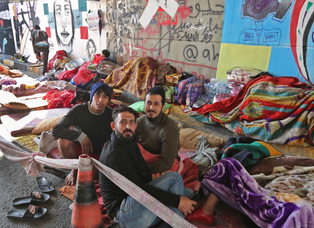 Iraqi anti-government protesters are pictured where they sleep on the side of a road surrounded by graffiti the Iraqi capital Baghdad's Tahrir square on Wednesday. — AFP