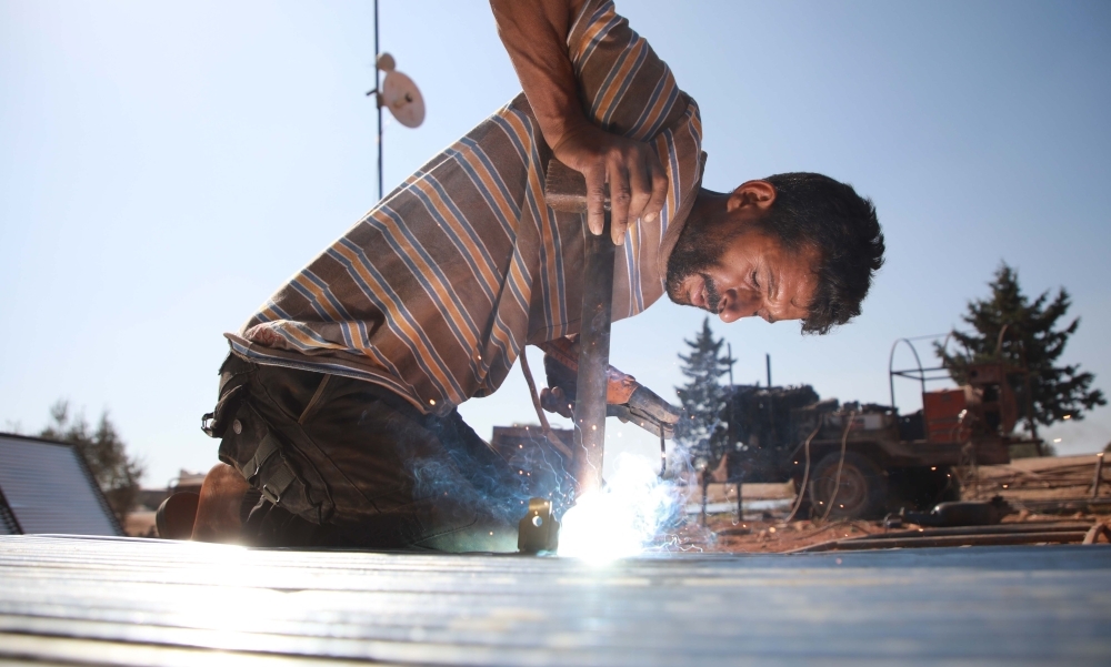 Jumaa Al-Mustayf welds metal pipes at a camp for the displaced near the town of Hazzanu, about 20 kilometers northwest of the city of Idlib, on September 30, 2019. -AFP