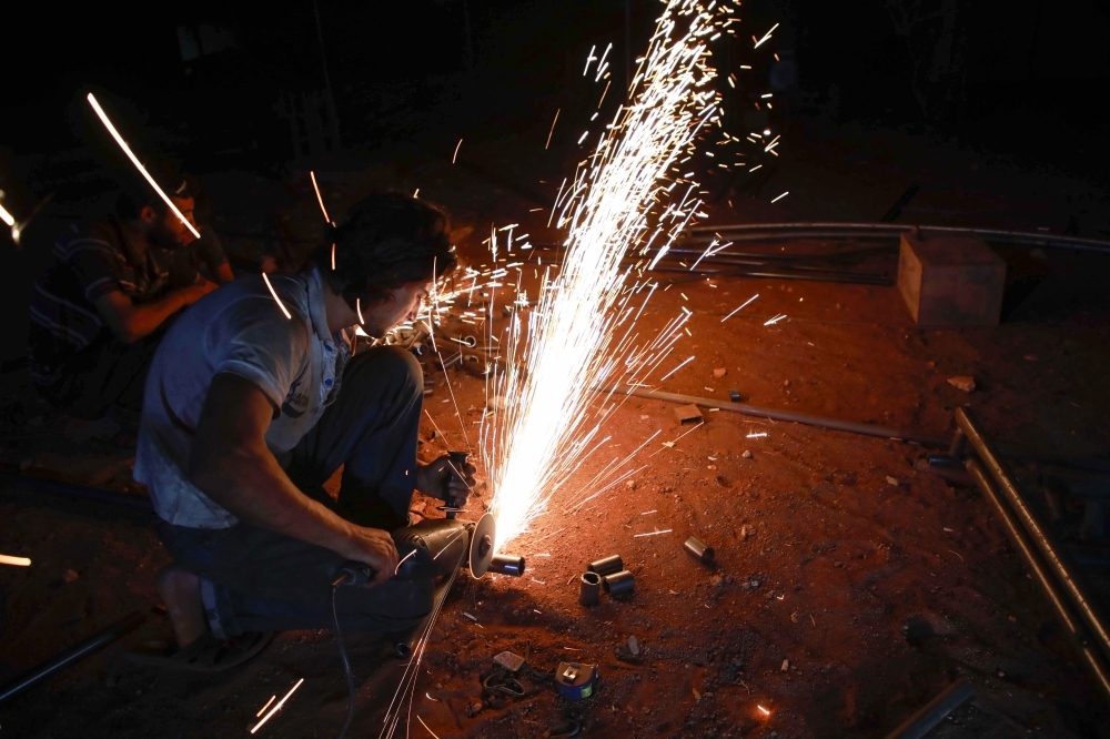 Jumaa Al-Mustayf welds metal pipes at a camp for the displaced near the town of Hazzanu, about 20 kilometers northwest of the city of Idlib, on September 30, 2019. -AFP
