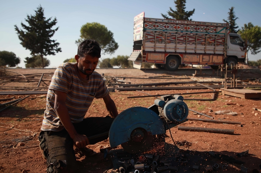 Jumaa Al-Mustayf welds metal pipes at a camp for the displaced near the town of Hazzanu, about 20 kilometers northwest of the city of Idlib, on September 30, 2019. -AFP