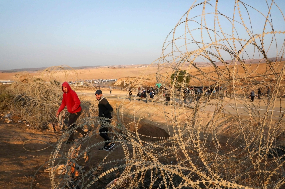 Palestinian labourers wait to cross illegally into Israeli areas through a hole in Israel's illegal barrier wall on November 20, 2019, in the southern Israeli city of Beer Sheva. -AFP