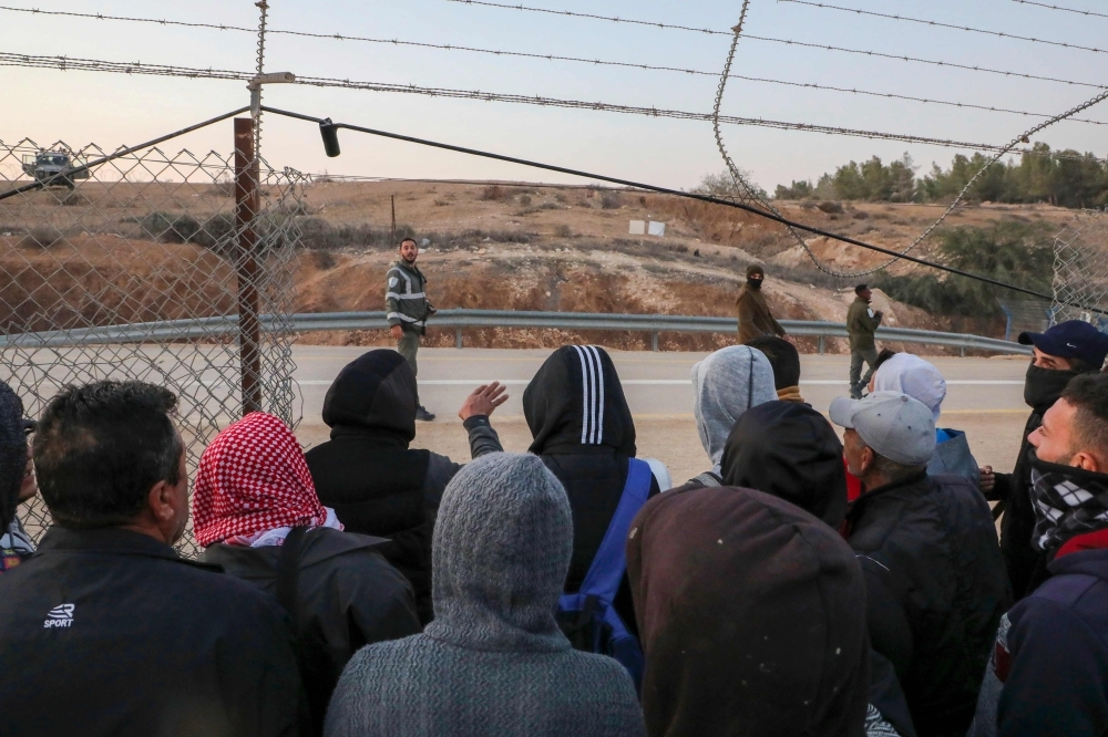Palestinian labourers wait to cross illegally into Israeli areas through a hole in Israel's illegal barrier wall on November 20, 2019, in the southern Israeli city of Beer Sheva. -AFP