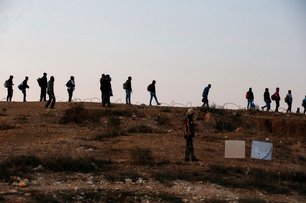 Palestinian labourers wait to cross illegally into Israeli areas through a hole in Israel's illegal barrier wall on November 20, 2019, in the southern Israeli city of Beer Sheva. -AFP