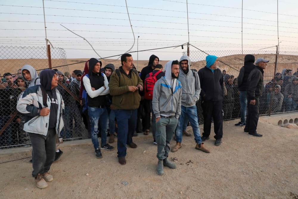 Palestinian labourers wait to cross illegally into Israeli areas through a hole in Israel's illegal barrier wall on November 20, 2019, in the southern Israeli city of Beer Sheva. -AFP