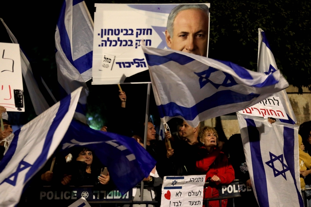 Supporters of Israeli Prime Minister Benjamin Netanyahu wave flags and placards as they rally to express their solidarity, outside his Jerusalem office on Saturday. -AFP