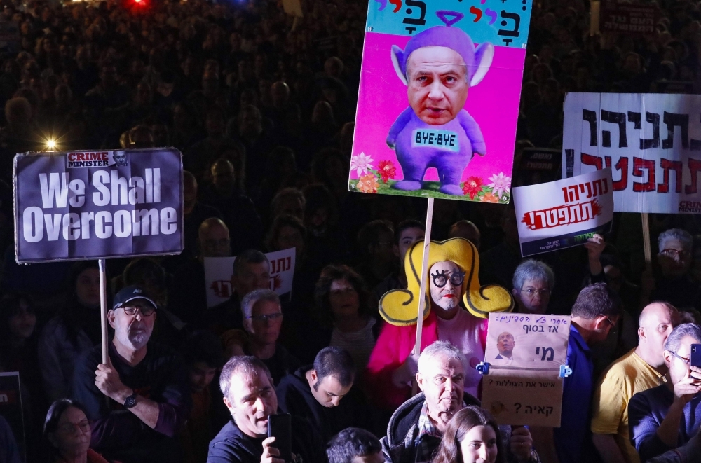 Supporters of Israeli Prime Minister Benjamin Netanyahu wave flags and placards as they rally to express their solidarity, outside his Jerusalem office on Saturday. -AFP