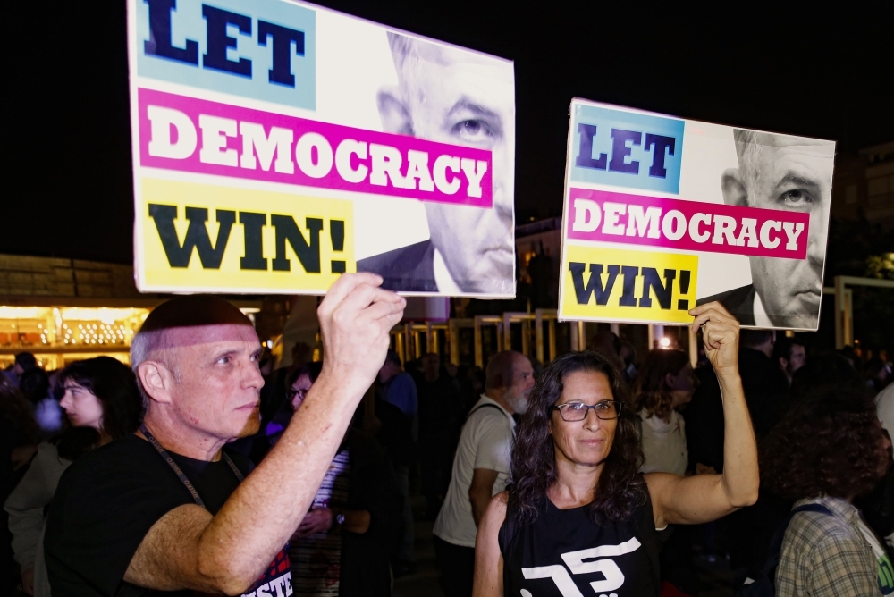 Supporters of Israeli Prime Minister Benjamin Netanyahu wave flags and placards as they rally to express their solidarity, outside his Jerusalem office on Saturday. -AFP