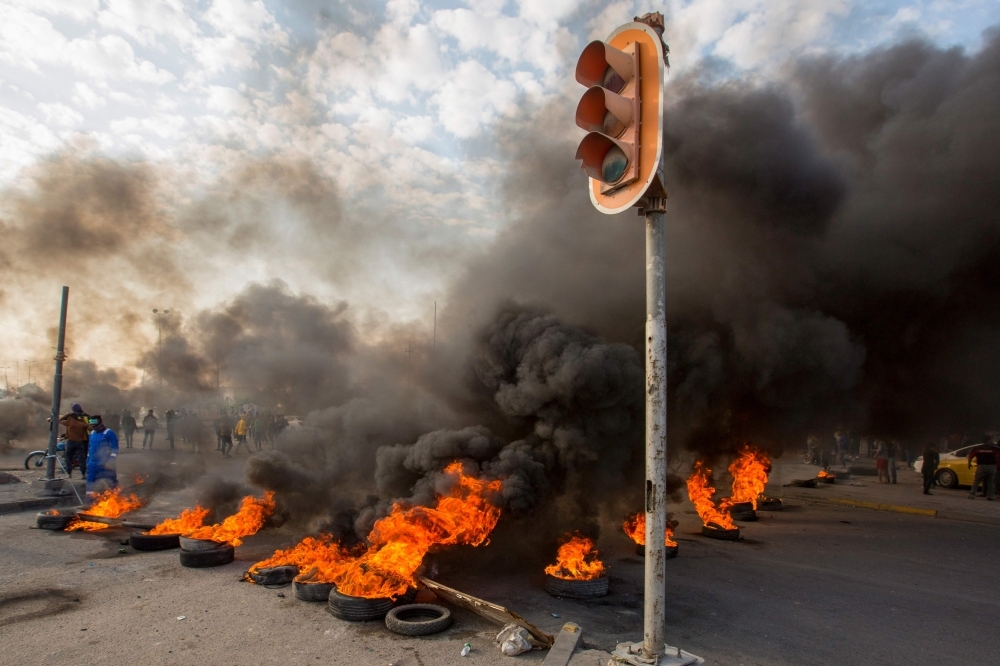 Smoke billows from burning tires during a demonstration in the southern city of Basra on Sunday, as protesters cut-off roads and activists call for a general strike. -AFP