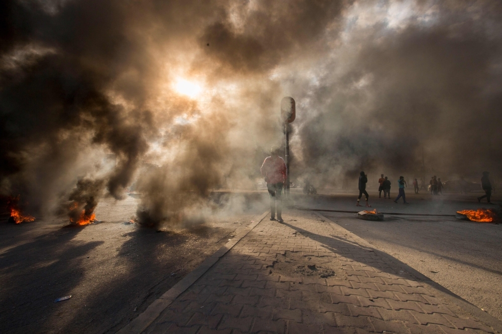 Smoke billows from burning tires during a demonstration in the southern city of Basra on Sunday, as protesters cut-off roads and activists call for a general strike. -AFP