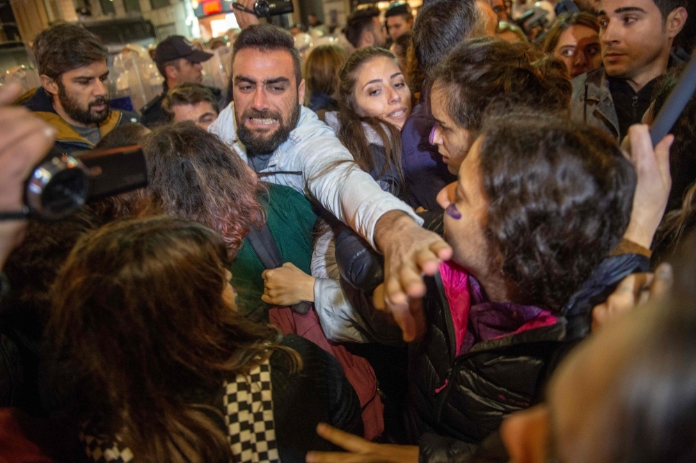 A Turkish riot police officer uses a non-lethal hand-held weapon during clashes with women's rights activists as they take part in a march towards Taksim Square in Istanbul on Monday. -AFP