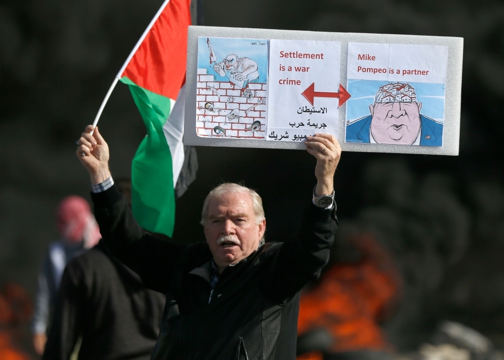 A Palestinian protester holds up a placard in the West Bank city of Ramallah on Tuesday as Palestinians stage a 