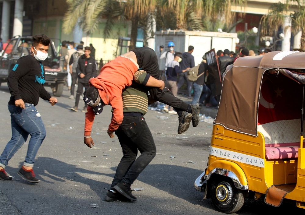 Iraqi youths duck as they run off amid clashes between anti-government demonstrators and security forces in the capital Baghdad's Al-Rasheed street near Al-Ahrar bridge on Tuesday. — AFP