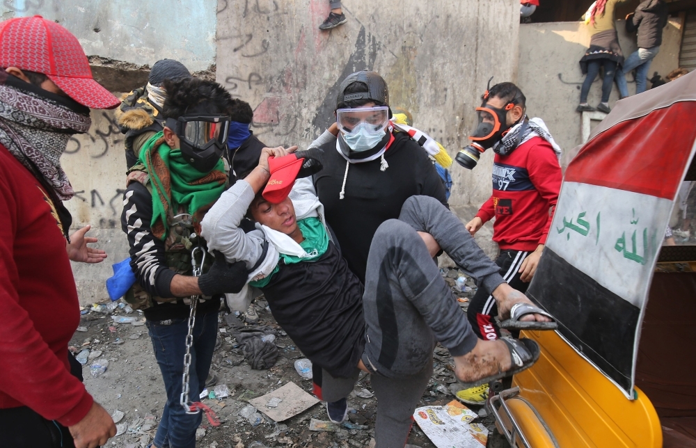 Iraqi youths duck as they run off amid clashes between anti-government demonstrators and security forces in the capital Baghdad's Al-Rasheed street near Al-Ahrar bridge on Tuesday. — AFP
