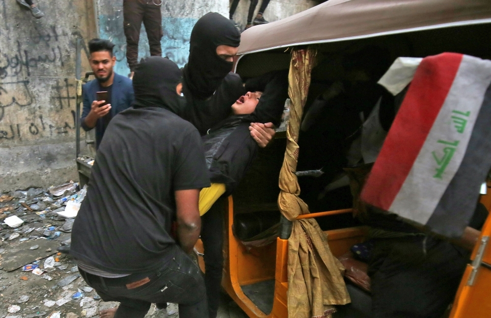 Iraqi demonstrators help an injured youth on Al-Rashid street in the capital Baghdad, amid ongoing anti-government protests, on Wednesday. — AFP