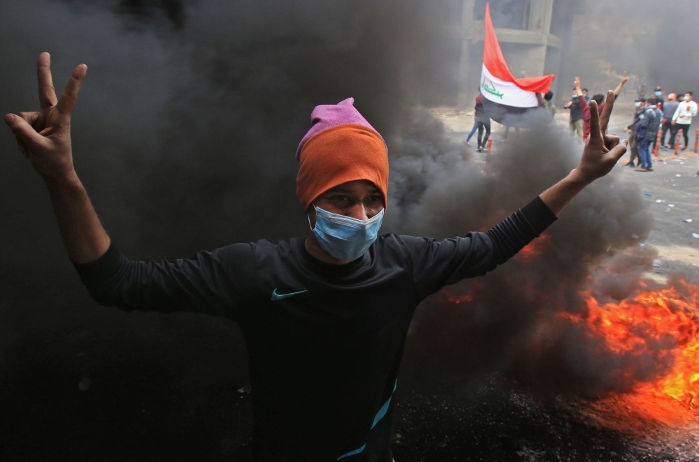 Iraqi demonstrators help an injured youth on Al-Rashid street in the capital Baghdad, amid ongoing anti-government protests, on Wednesday. — AFP
