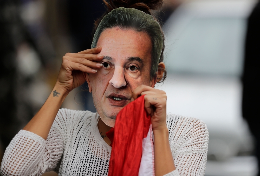 A Lebanese anti-government protester hold a mask of Lebanon's Central Bank Governor Riad Salameh during a protest in front of the central bank headquarters in Beirut to protest against the economic policies of the bank on Wednesday. — AFP