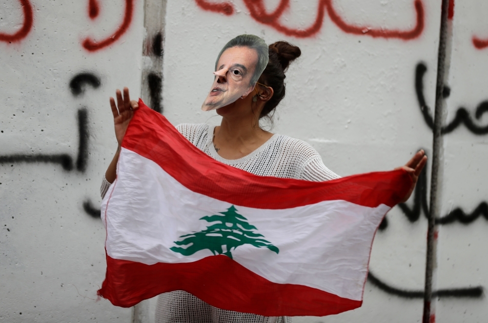 A Lebanese anti-government protester hold a mask of Lebanon's Central Bank Governor Riad Salameh during a protest in front of the central bank headquarters in Beirut to protest against the economic policies of the bank on Wednesday. — AFP