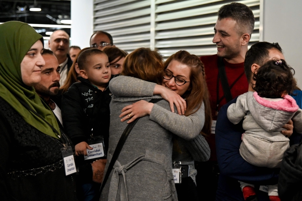 Syrian refugees Ibrahim Bitar, 42, rear right with red jersey, and his sister Iman Bitar, center from behind, react after arriving with other Syrian refugees at Rome's Fiumicino international airport as part of a humanitarian corridor on Wednesday. — AFP