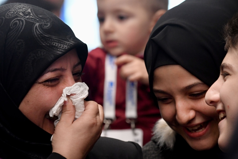 Syrian refugees Ibrahim Bitar, 42, rear right with red jersey, and his sister Iman Bitar, center from behind, react after arriving with other Syrian refugees at Rome's Fiumicino international airport as part of a humanitarian corridor on Wednesday. — AFP