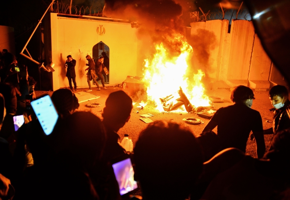 Iraqi demonstrators gather as flames start consuming Iran's consulate in Al-Najaf on Wednesday. (AFP)