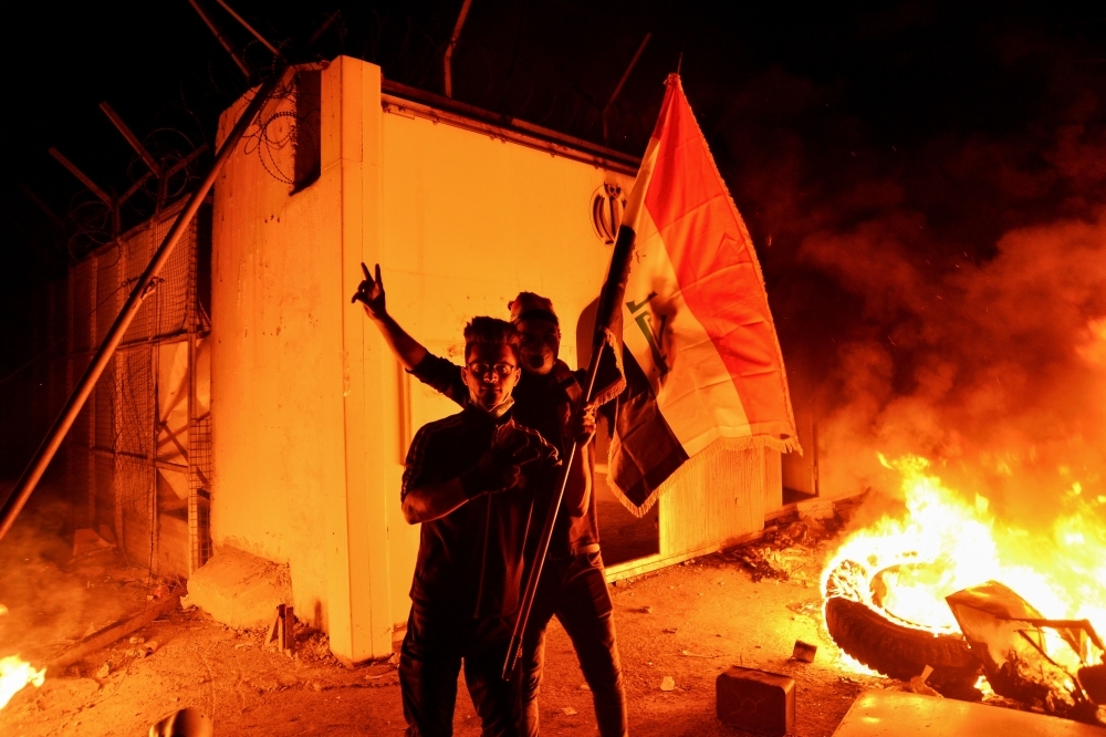 Iraqi demonstrators gesture as flames start consuming Iran's consulate in the southern Iraqi Shiite holy city of Najaf on Wednesday, two months into the country's most serious social crisis in decades. — AFP 