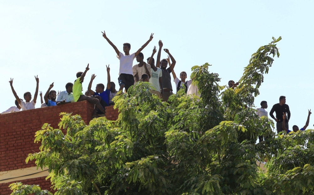 Sudanese students protest on the roof of a building overseeing a mosque in the capital Khartoum as hardline cleric Mohamed Ali Jazuli, not pictured, gives a sermon during Friday prayers. — AFP