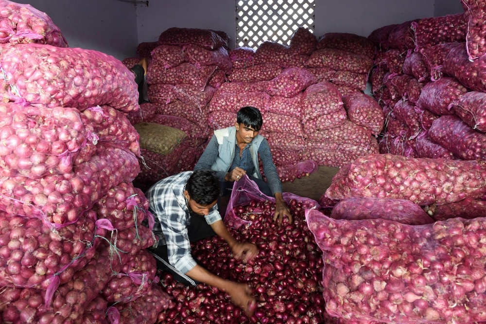 Laborers sort out onions in a shop at a market in Ahmedabad, Gujarat, India, on Friday. — AFP