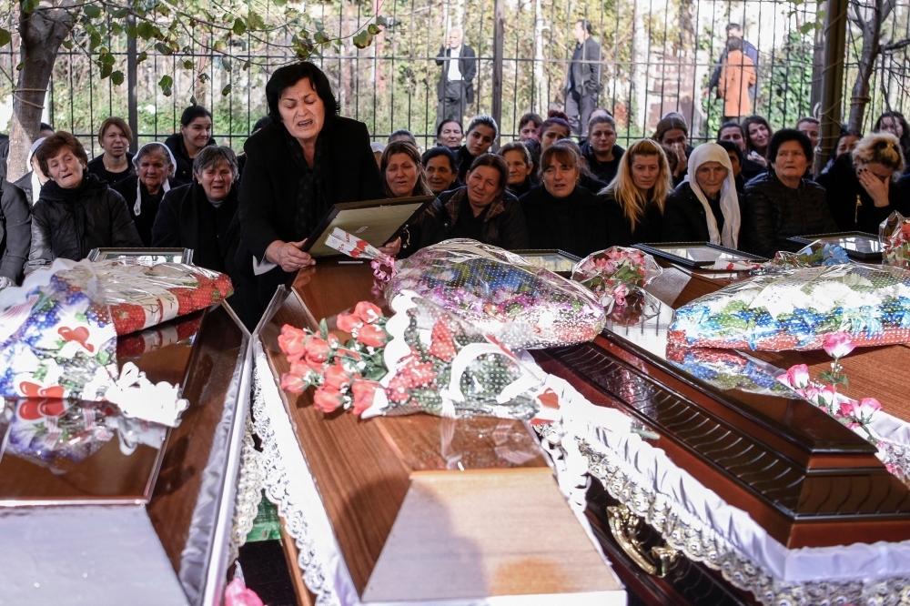 Relatives mourn over the coffins of six members of the Cara family who died during the earthquake in Thumane, Albania, on Friday. — AFP