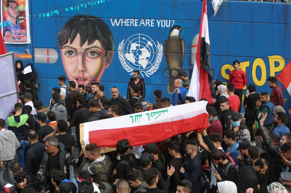 Iraqi mourners carry the coffin of Haidar Ahmed Kazem, a high school student who was killed a day earlier, during his funeral procession in Tahrir square in the capital Baghdad, on Sunday. -AFP