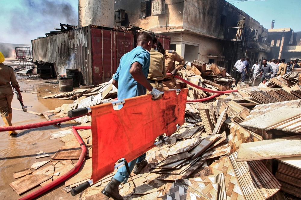 A Sudanese paramedic walks with a stretcher as others search for victims at the scene of a fire at a tile manufacturing unit in an industrial zone in north Khartoum on Tuesday. — AFP