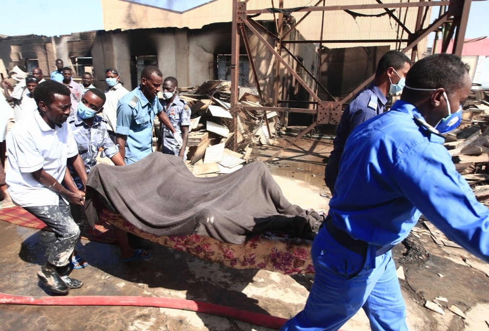 A Sudanese paramedic walks with a stretcher as others search for victims at the scene of a fire at a tile manufacturing unit in an industrial zone in north Khartoum on Tuesday. — AFP