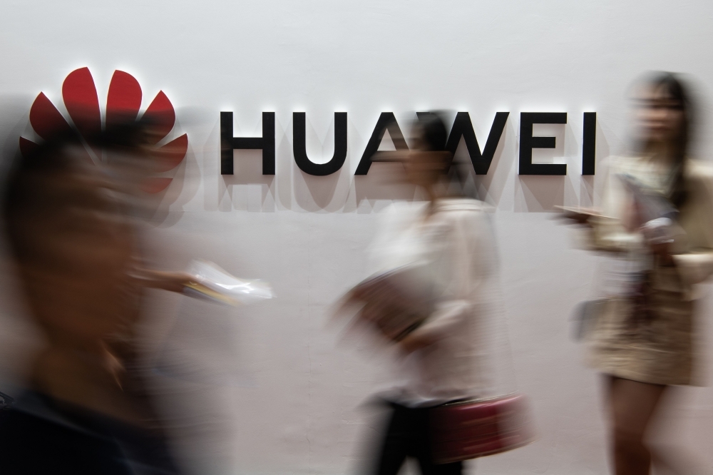 People walk past a Huawei logo during the Consumer Electronics Expo in Beijing in this Aug. 2, 2019 file photo. — AFP