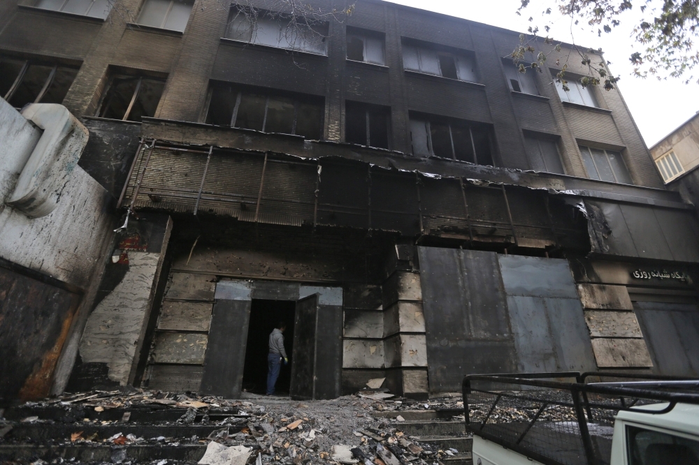 An Iranian man stands at the burned branch of a local bank that was damaged during demonstrations against petrol price hikes in Shahriar, west of Tehran, in this November 20, 2019 file photo. — AFP