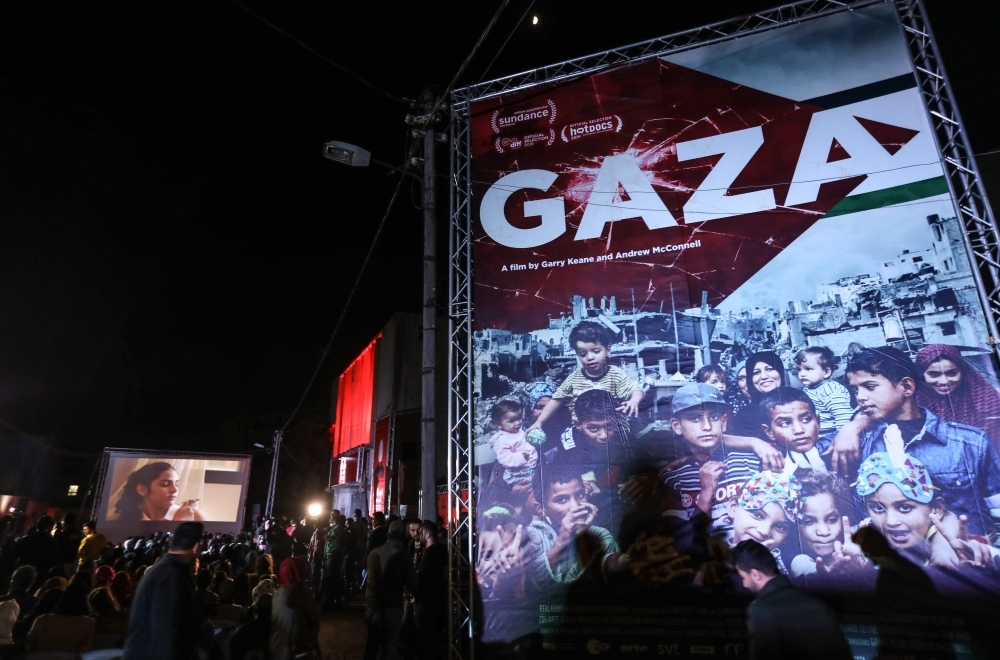 Palestinians watch a film during the opening ceremony of the Red Carpet Human Rights Film Festival in Gaza-Karama Palestine, in front of the abandoned Cinema Amer building in Gaza City, on Wednesday. — AFP