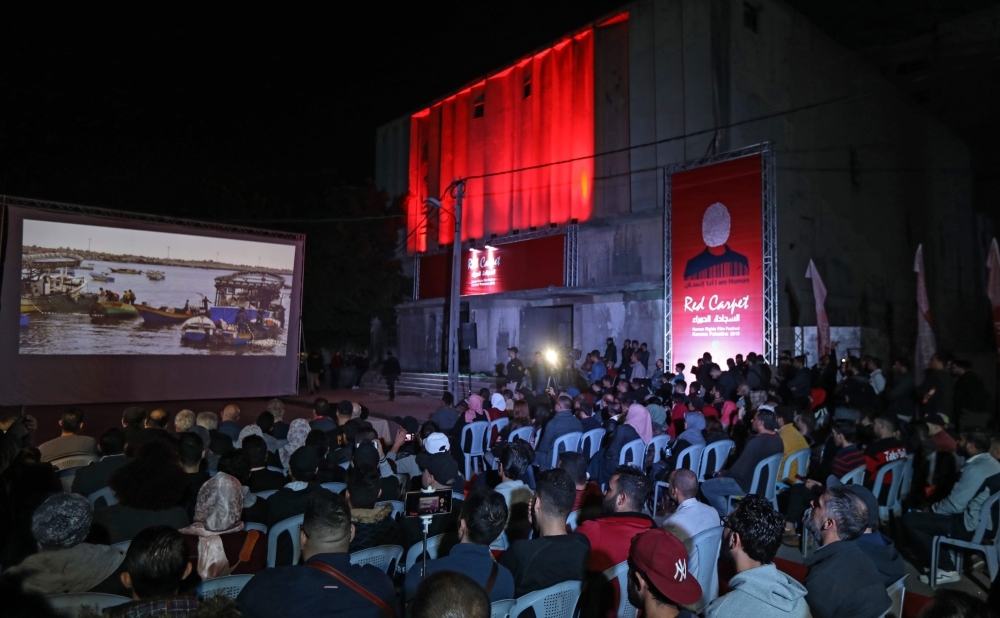 Palestinians watch a film during the opening ceremony of the Red Carpet Human Rights Film Festival in Gaza-Karama Palestine, in front of the abandoned Cinema Amer building in Gaza City, on Wednesday. — AFP