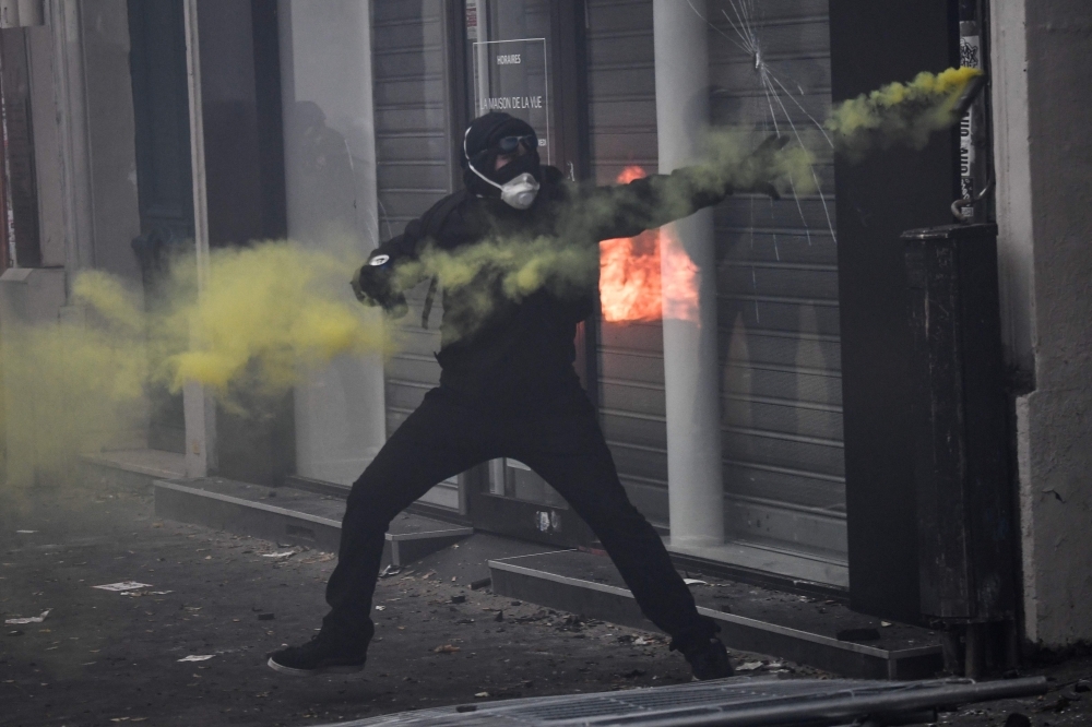 CRS riot police stand as fire is seen in the background during a rally against the pension overhauls, in Paris, on Thursday. — AFP
