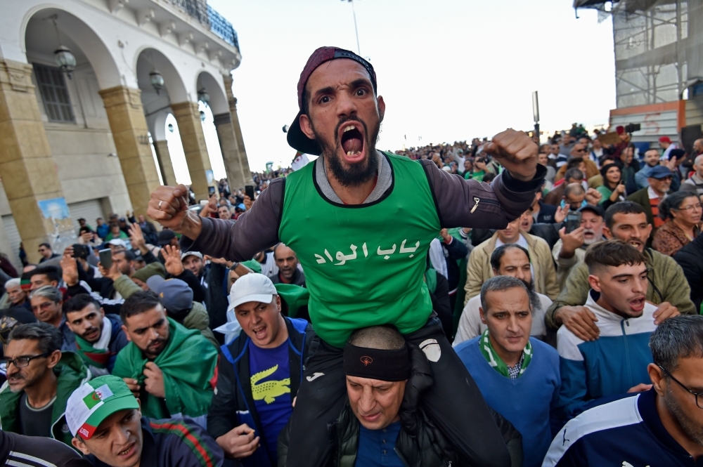 An Algerian demonstrator raises a red card that reads 