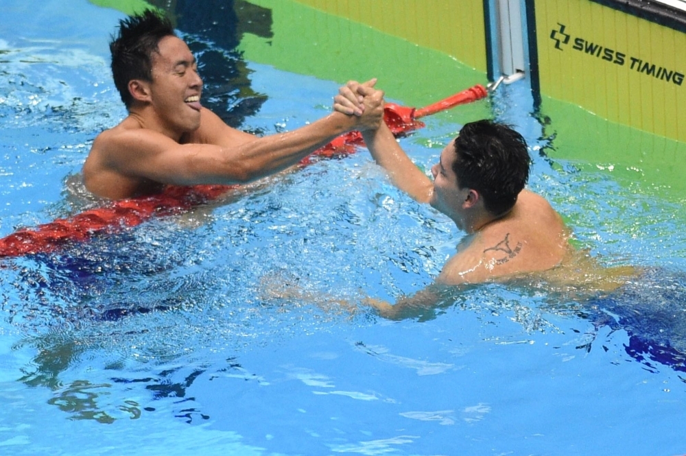 Singapore's Joseph Schooling (R) celebrates with compatriot Zhen Wen (L) after winning the men's 100m swimming butterfly during the SEA Games (Southeast Asian Games) at the Aquatic center in Clark, Capas, Tarlac province, north of Manila, on Friday. — AFP