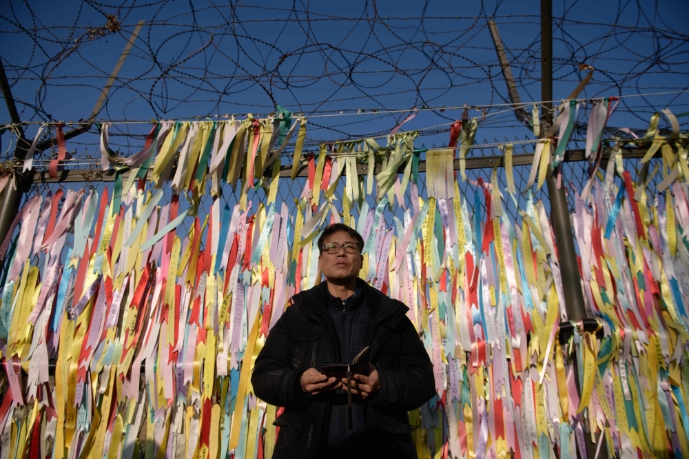 Hwang In-cheol stands before a fence covered in 'peace ribbons' during an event calling for the release of his father by North Korea, at the Imjingak peace park near the Demilitarized Zone (DMZ) separating the two Koreas, in Paju on Sunday. -AFP