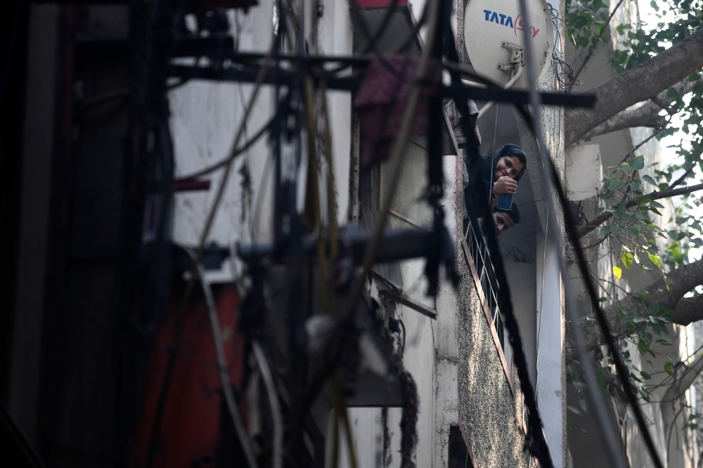 Residents look on near a factory site where a fire broke out a day before, in Anaj Mandi area of New Delhi on Sunday. -AFP