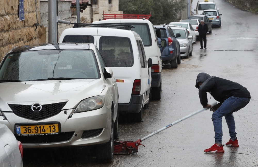 A Palestinian youth checks a car as vehicles with their tires slashed are pictured in the Palestinian neighborhood of Shuafat, neighboring the Israeli settlement of Ramat Shlomo, in Israeli annexed east Jerusalem, on Monday. — AFP
