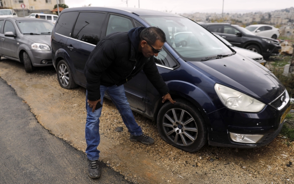 A Palestinian youth checks a car as vehicles with their tires slashed are pictured in the Palestinian neighborhood of Shuafat, neighboring the Israeli settlement of Ramat Shlomo, in Israeli annexed east Jerusalem, on Monday. — AFP